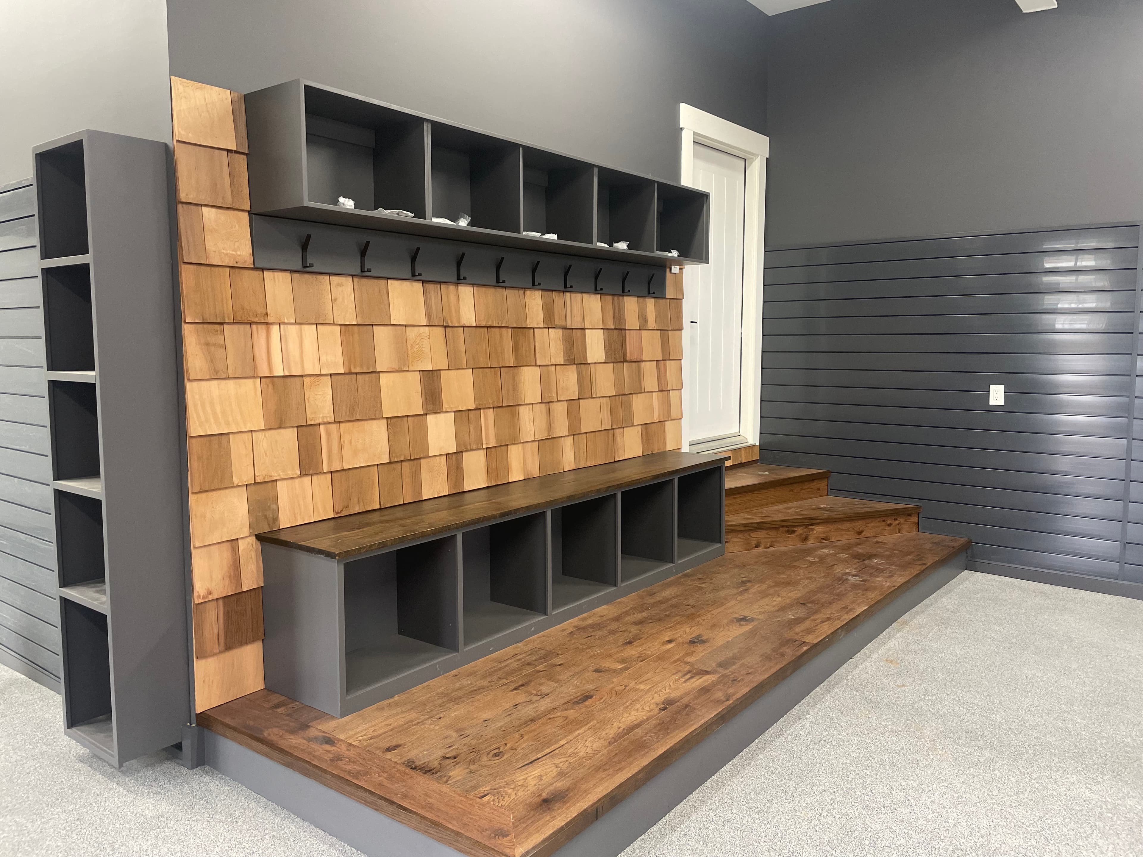 Garage utility organizer with cubbies, bench storage, and a checkerboard wood panel.
