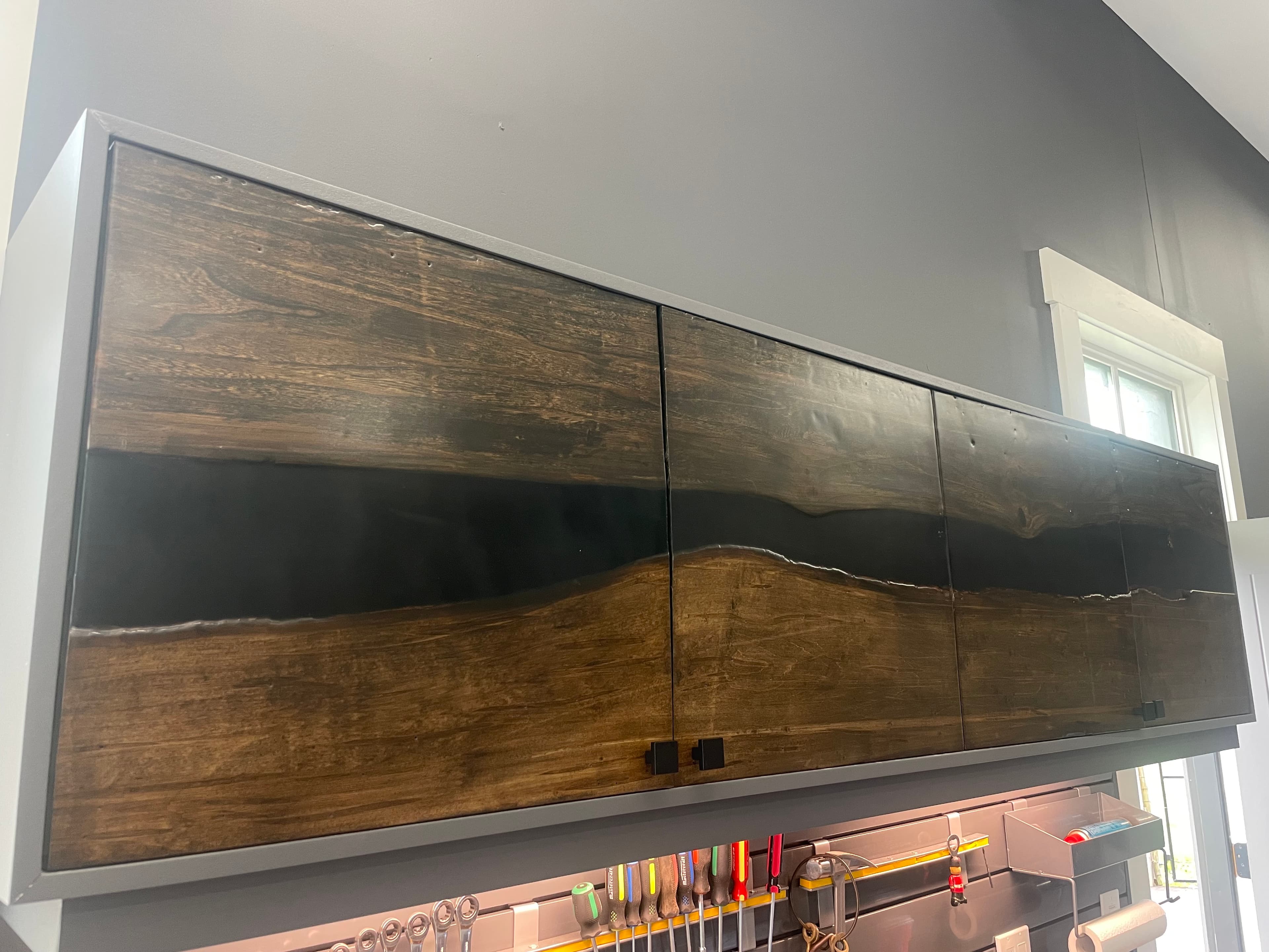 Wall-mounted cabinetry with a long timber front above a workshop counter.