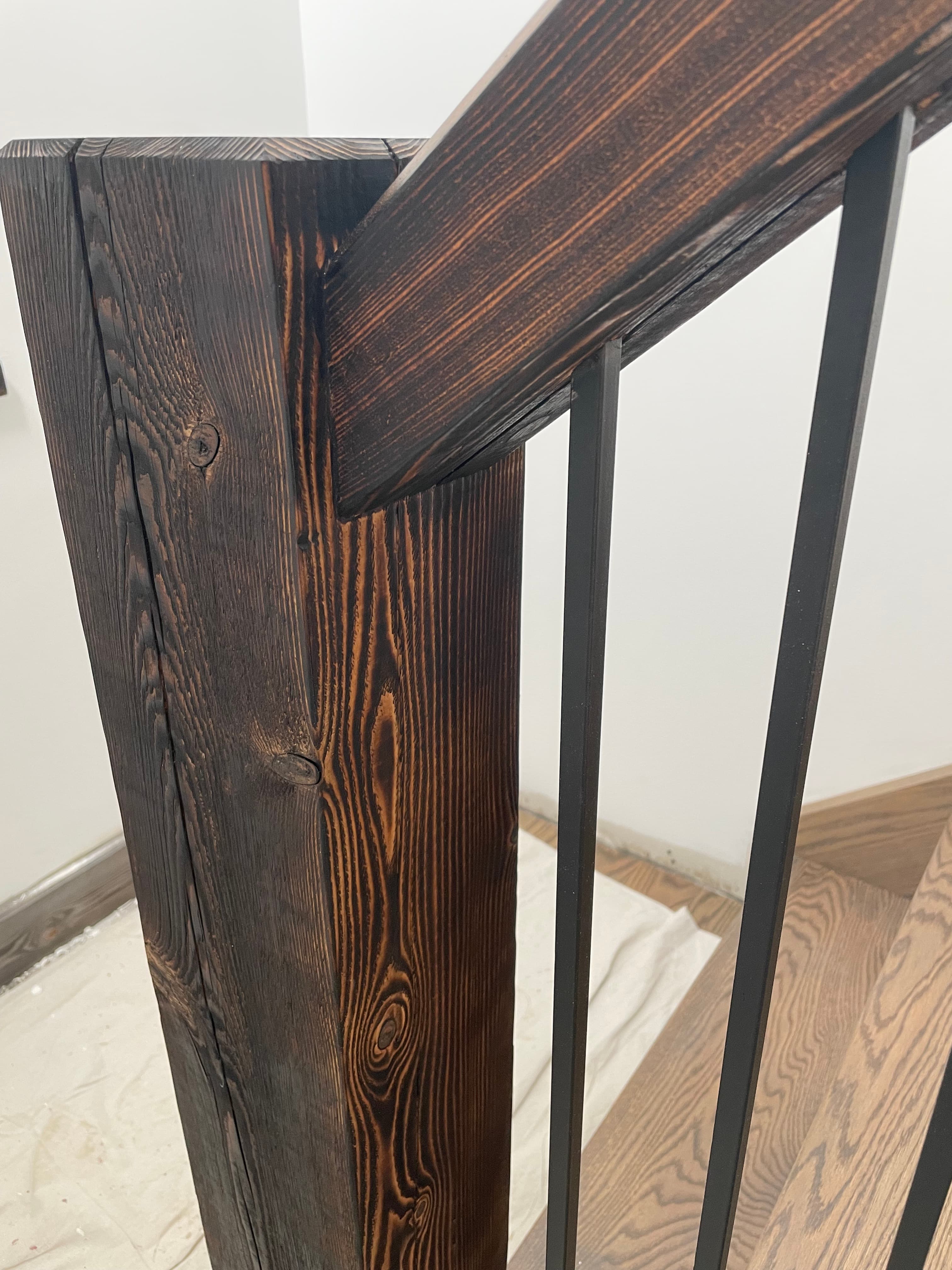 Dark brushed timber stair rail detail with vertical metal balusters.