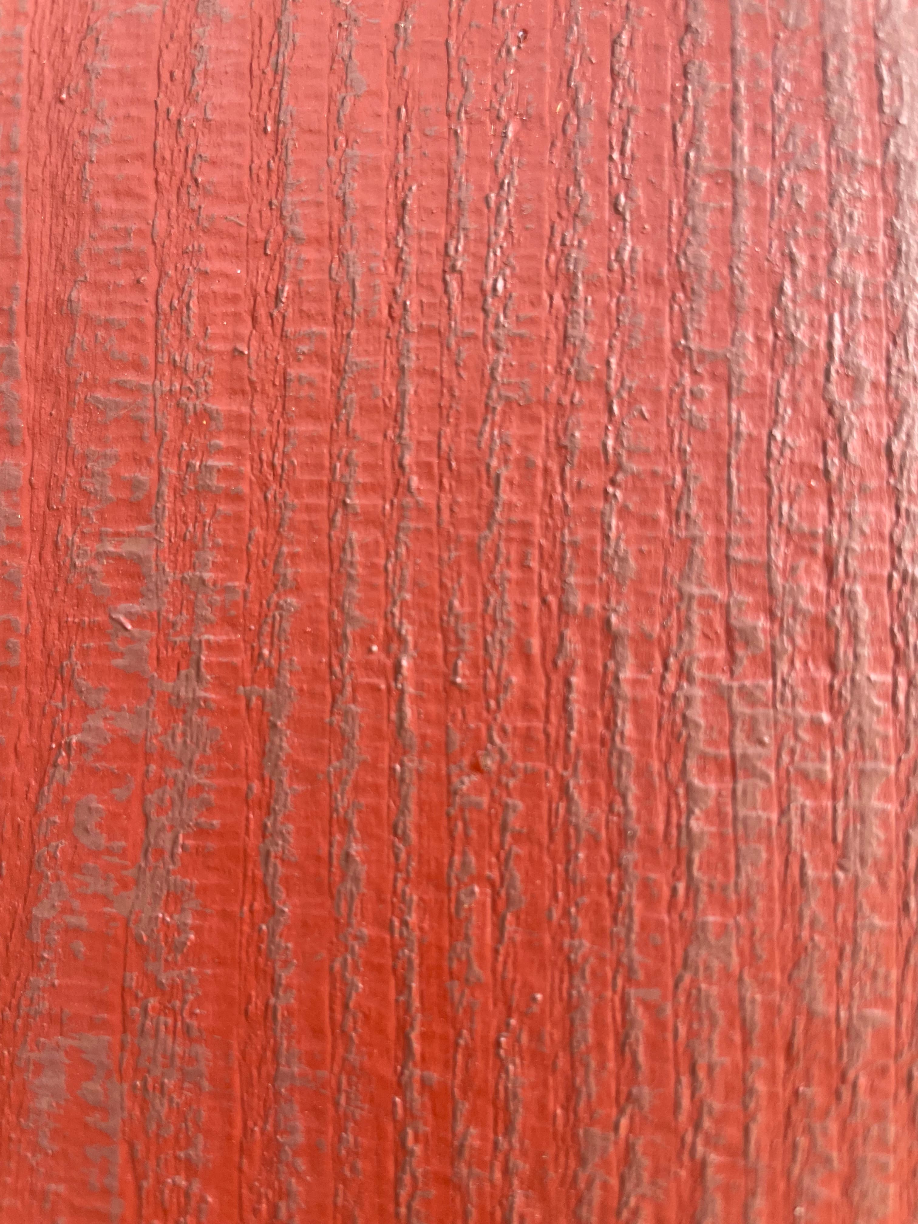 Close detail of red dry-brushed cabinet texture with visible raised grain.