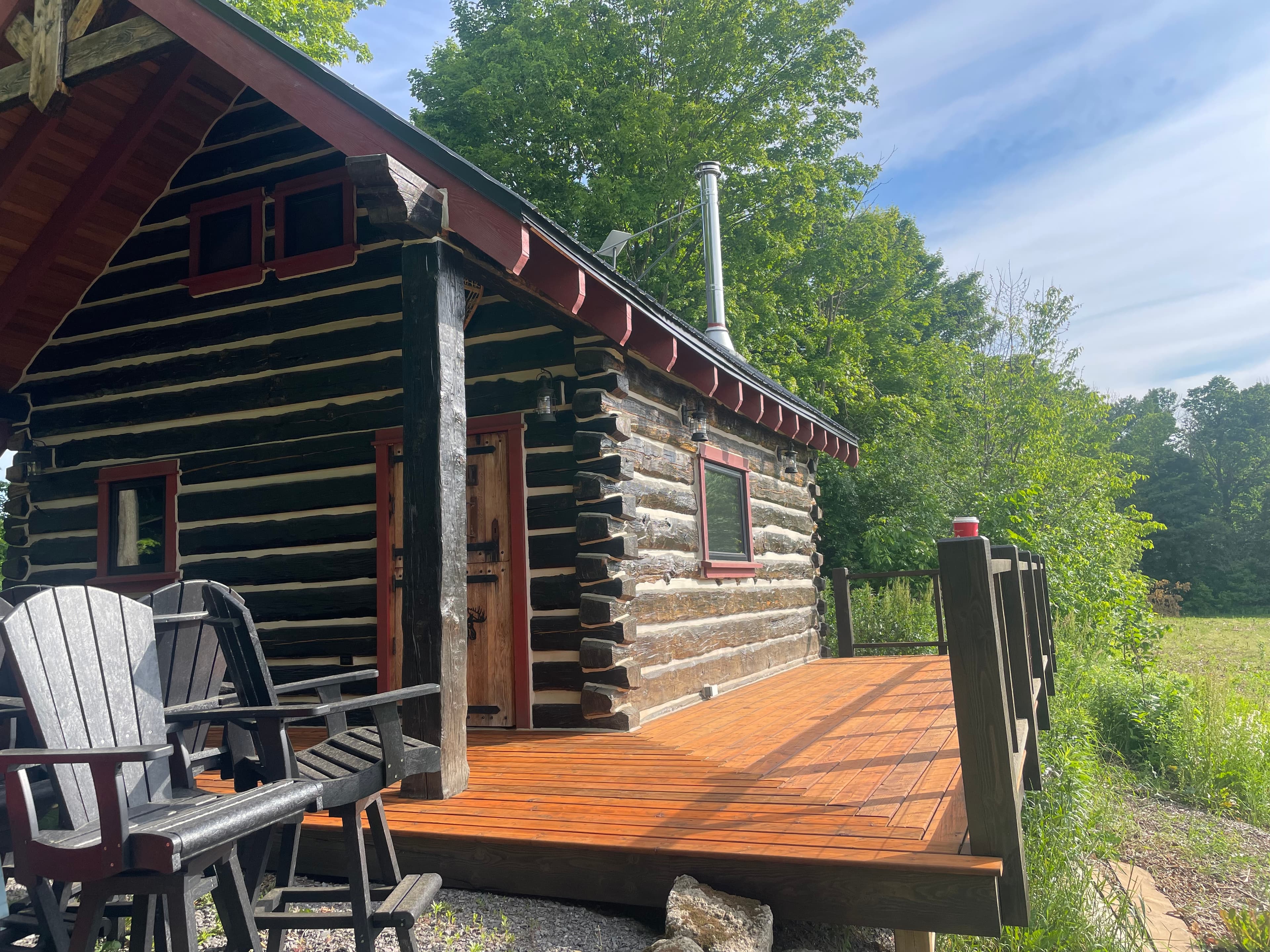 Cabin wraparound deck with railing and log cabin wall beyond.