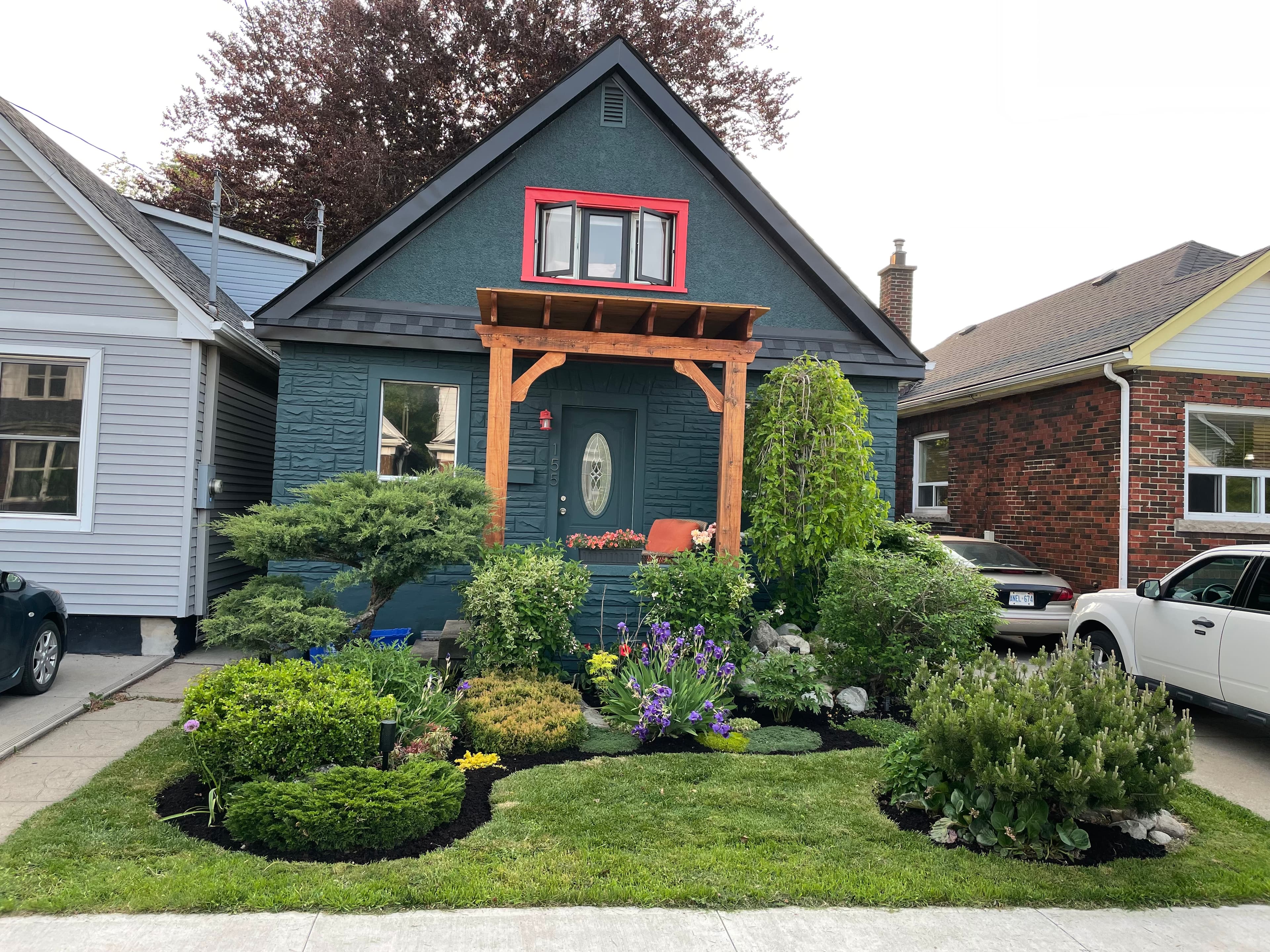 Updated house facade with dark cladding, red entry trim, and a new porch frame.