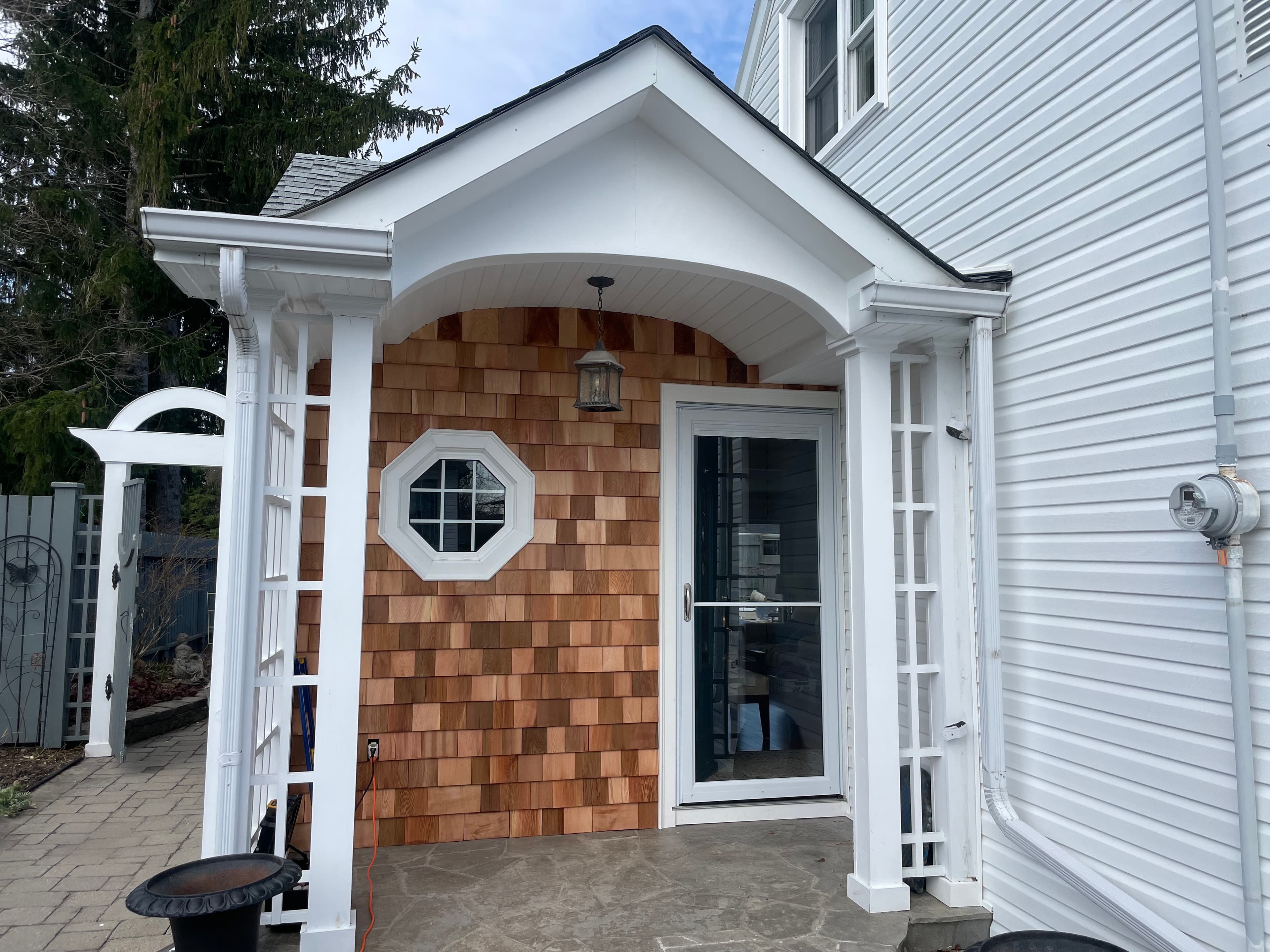 Custom porch entry with cedar shingle detailing and white exterior trim.