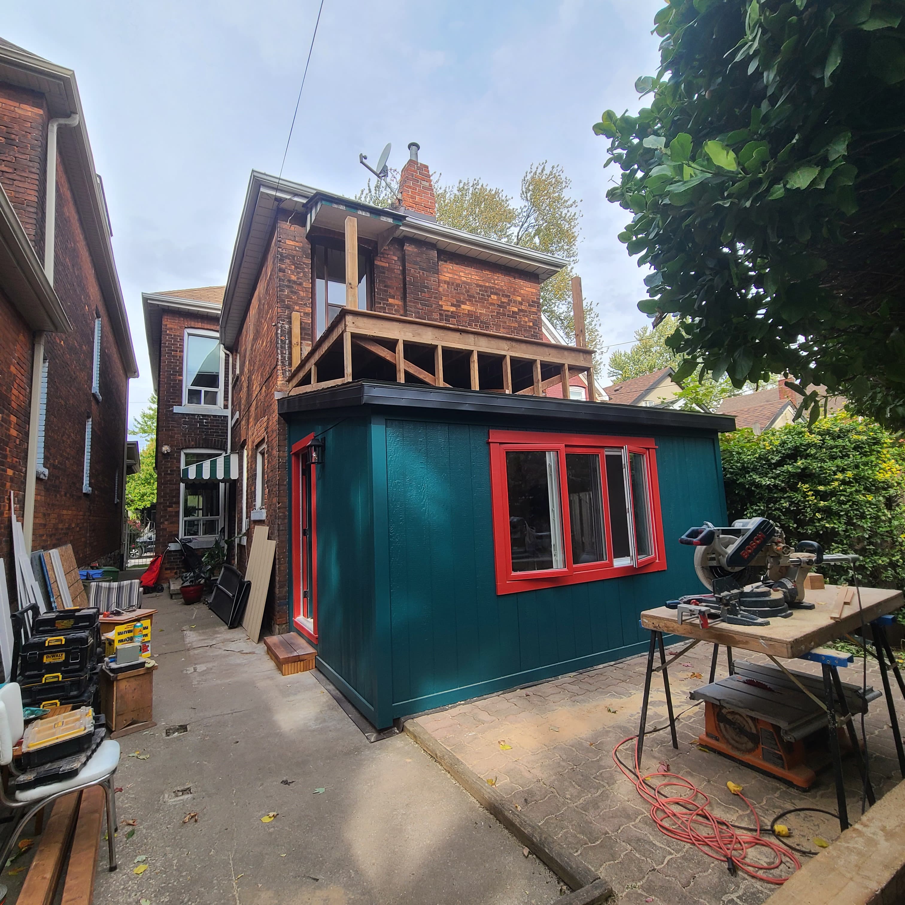 Rear addition exterior under construction with new wall framing and cladding work in progress.